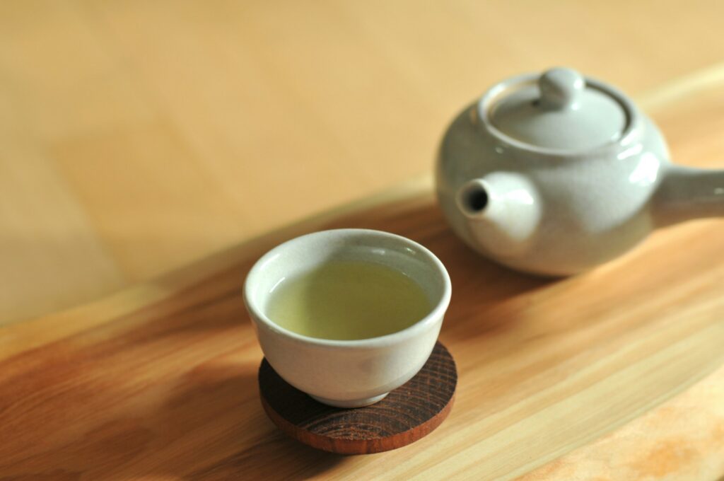 A cup of green tea beside a teapot