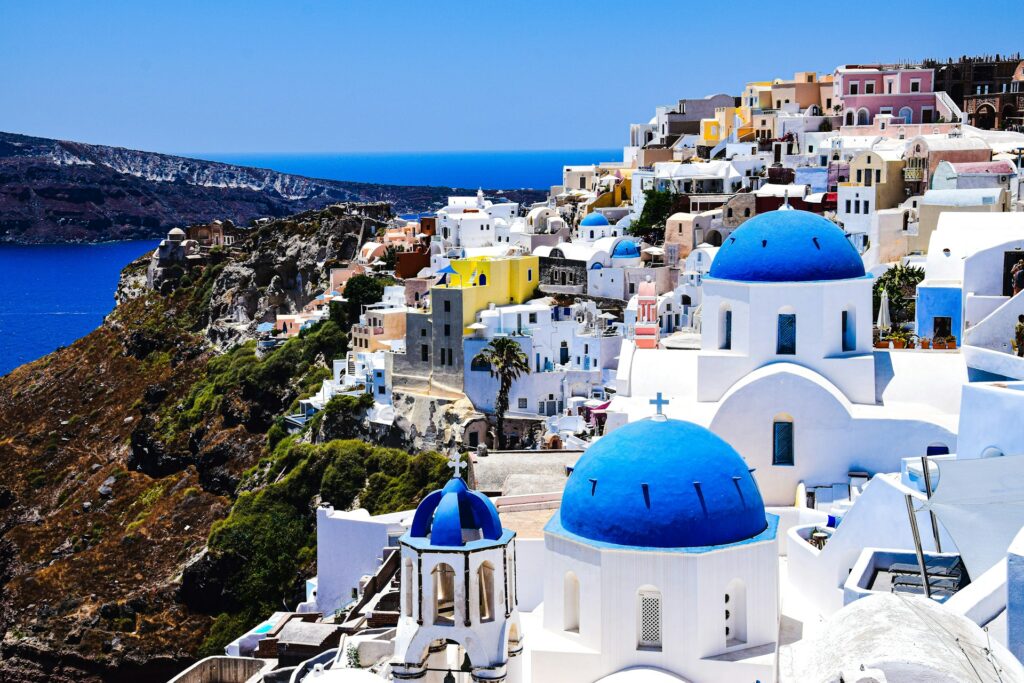 Blue and white buildings stacked against a scenic hillside