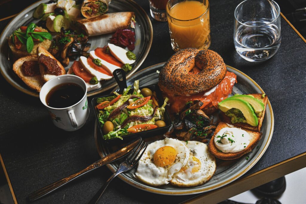hamburger, fried eggs, avocado slices, and bread on round gray plate

