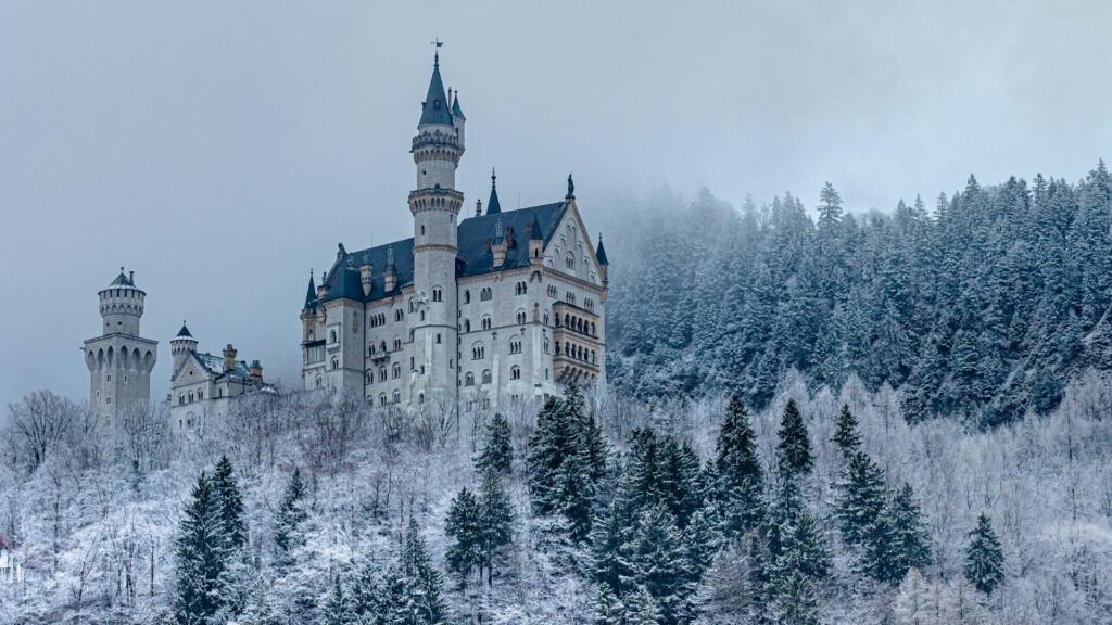 Schloss Neuschwanstein crests a snowy forest under overcast skies