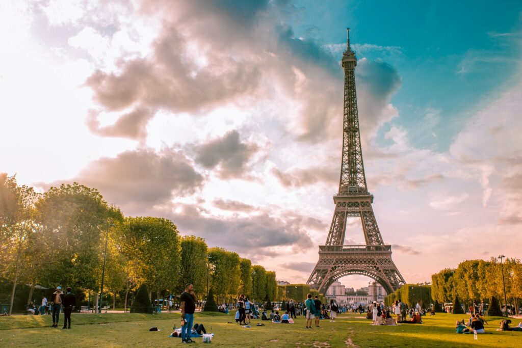 The Eiffel Tower against a bright blue sky, standing over lush greenery