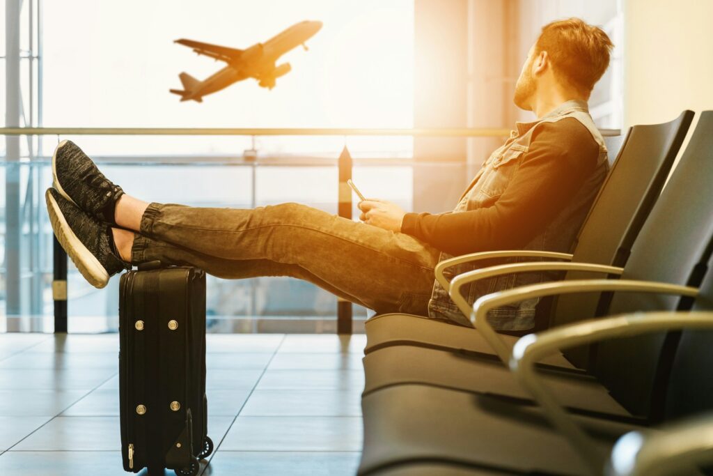 A man sitting in an airport lounge with his feet up on his suitcase.