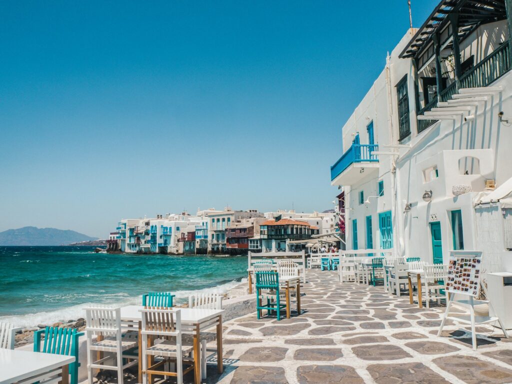 A romantic seaside town with clean white buildings, and a pristine outdoor seating area.