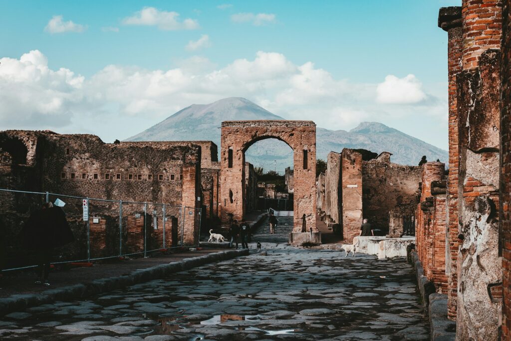 An ancient archway of Pompeii, with the slopes of Mount Vesuvius in the backdrop