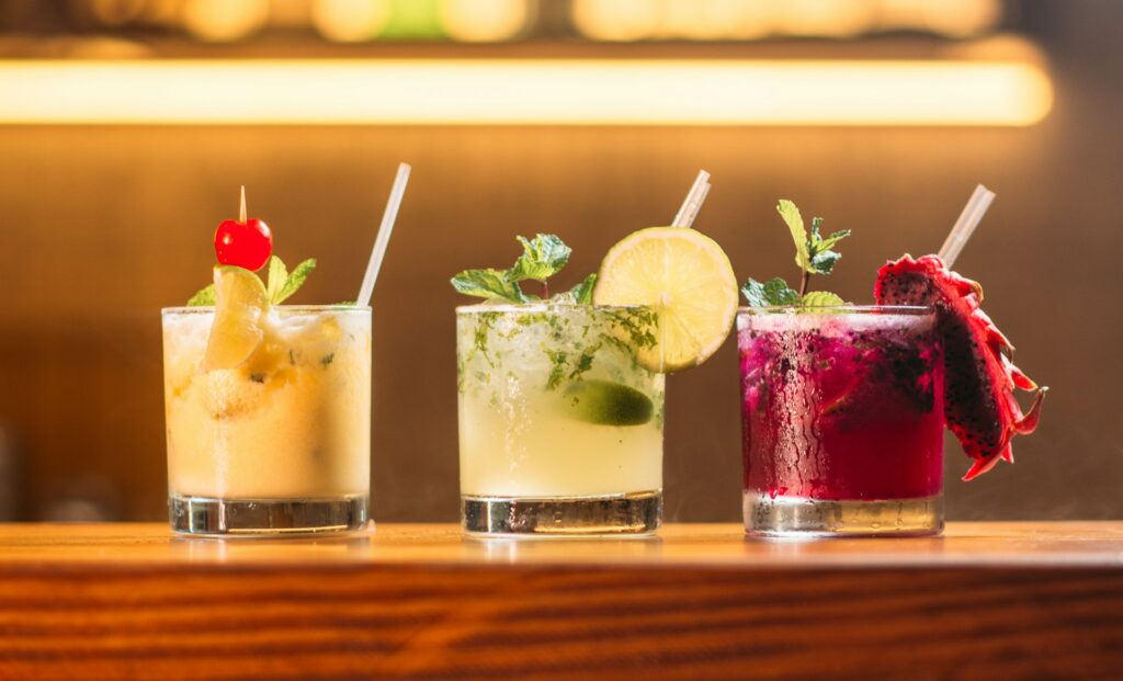 A row of three drinks on a bar counter